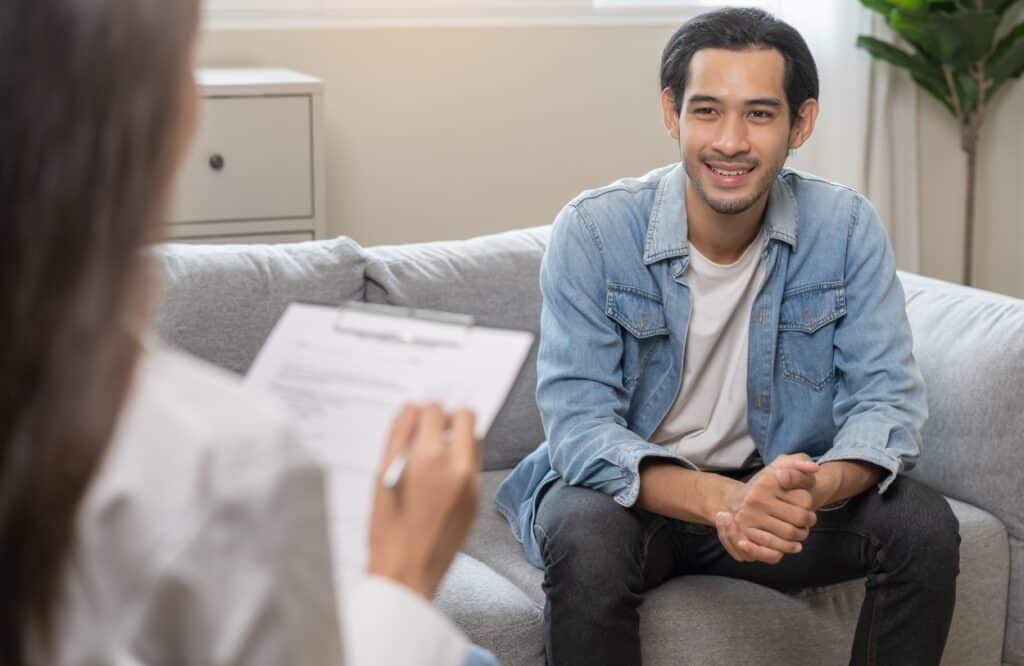 A young man talks to his therapist about his progress after starting tms treatment.